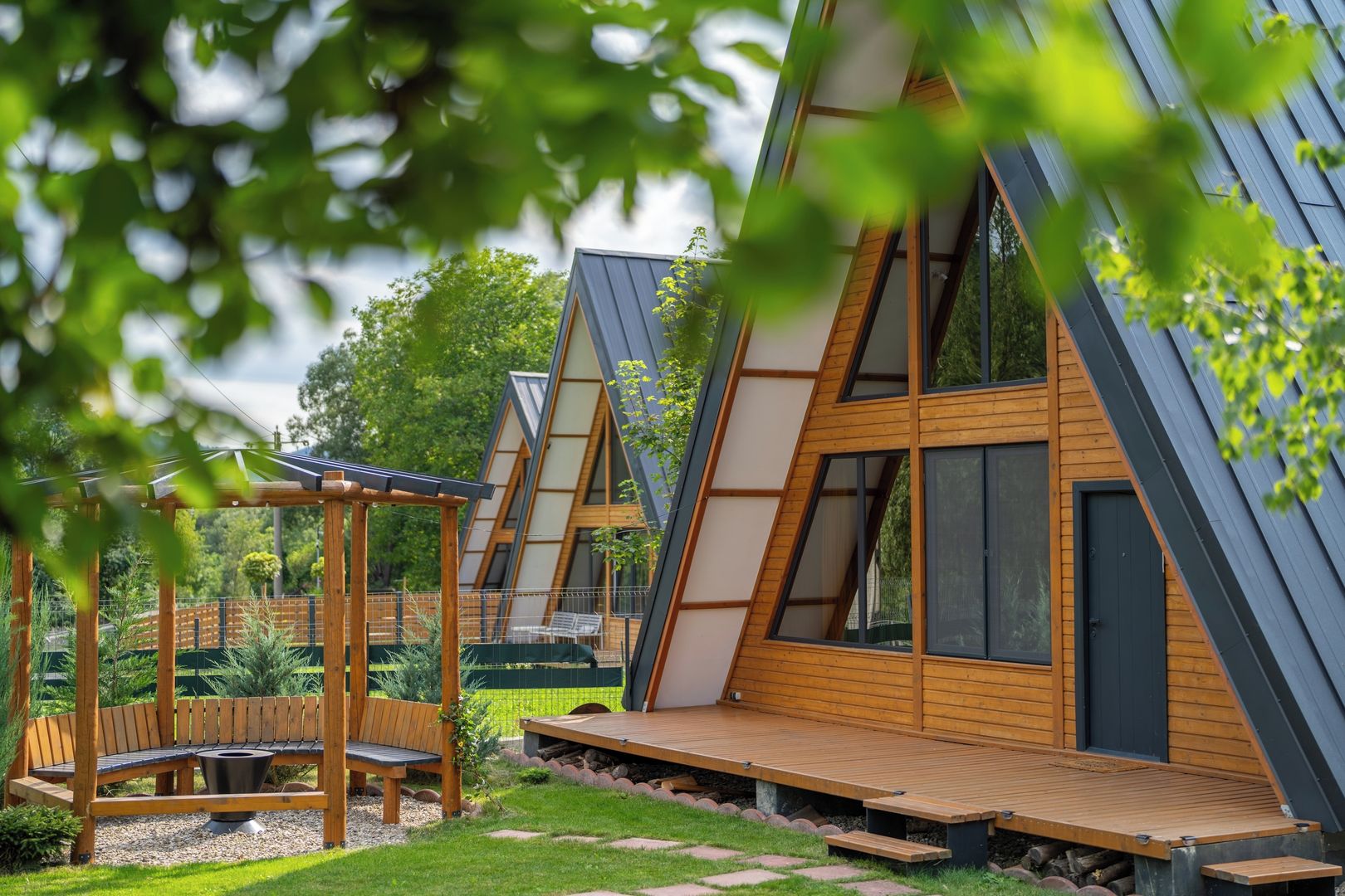 A modern, triangular-roofed building with a wooden deck and a seating area.
