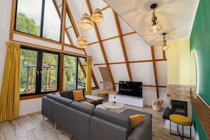 A modern living room with a large sofa, a flat-screen TV, and a fireplace.