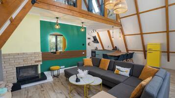 Een moderne woonkamer met een open haard, een bank, een eethoek en een keuken.