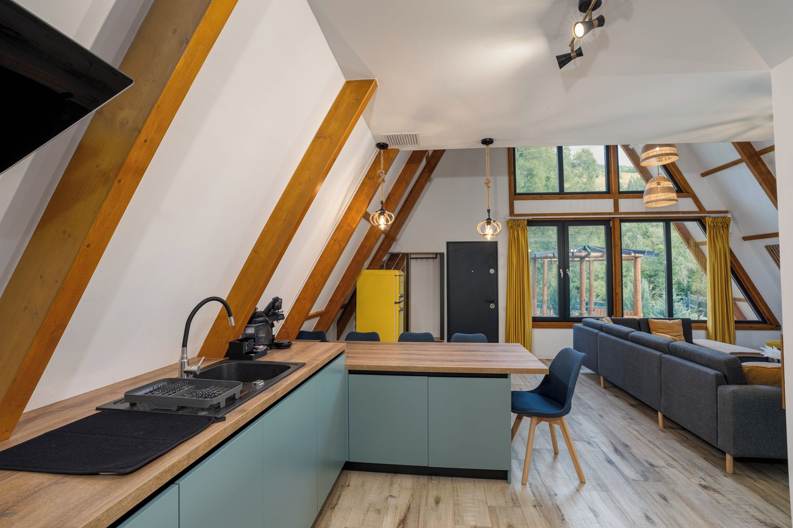 A modern loft with a kitchen, dining area, and a large window providing a view of the outdoors.