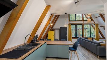 A modern loft with a kitchen, dining area, and a large window providing a view of the outdoors.