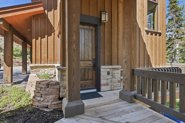 A wooden building with a porch, stone steps, and a door.