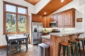 A kitchen with wooden cabinets, a stainless steel refrigerator, a microwave, and a granite countertop. - Rare 2 bedroom in The Colony! (Park City)