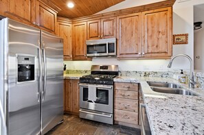 A kitchen with wooden cabinets, stainless steel appliances, a granite countertop, and a stainless steel sink.
