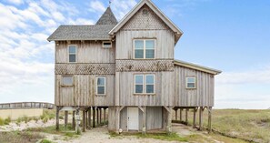 A two-story wooden house with a steep gabled roof, multiple windows, and a front porch. - The Gothic House with Beachfront (Pensacola)