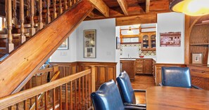 A wooden staircase leading to a dining area with a kitchen in the background. - The Gothic House with Beachfront (Pensacola)