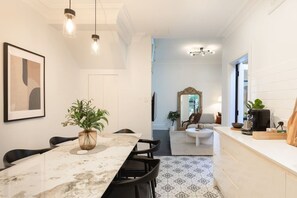 A modern kitchen with a marble countertop, a dining table with chairs, a coffee machine, and a potted plant. - Bondi Junction 4BR 2B Family Home + Secure Parking (Woollahra)