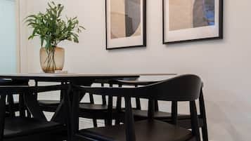 Un coin repas avec une table et des chaises, une plante en pot et deux œuvres d’art encadrées accrochées au mur.