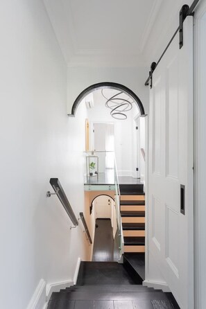 A narrow hallway with a staircase leading to a landing. - Bondi Junction 4BR 2B Family Home + Secure Parking (Woollahra)
