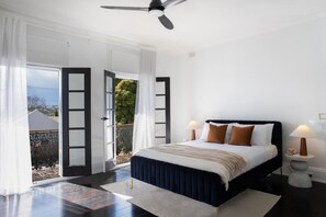 A bedroom with a bed, bedside lamps, a ceiling fan, and a view through open doors. - Bondi Junction 4BR 2B Family Home + Secure Parking (Woollahra)