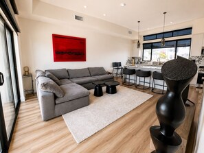 Ein modernes Wohnzimmer mit einem grauen Ecksofa, einem runden Couchtisch und einem einzigartigen, schwarzen Skulpturenstuhl.