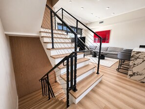 A modern interior with a staircase, a living area with a sofa, and a red accent wall. - All New Luxury 5-Level Home with Rooftop in the heart of LA, City Views, Parking (Los Angeles)