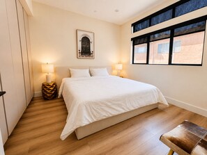 A bedroom with a bed, bedside lamps, a framed picture on the wall, and a window with blinds. - All New Luxury 5-Level Home with Rooftop in the heart of LA, City Views, Parking (Los Angeles)