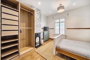 A bedroom with a bed, a wardrobe, a television, and a fireplace. - Quaint Cottage in Charming Evesham (Evesham)