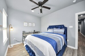 Ein Schlafzimmer mit einem Bett, einem Deckenventilator, einem Schreibtisch und einer Wandlampe.