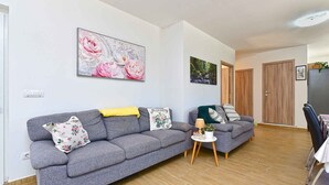 En moderne stue med en grå sofa, et lille sofabord og et spiseområde med en stol og et bord.