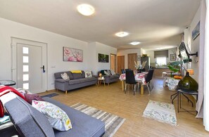 A living room with a sofa, a dining table, and chairs. There is a kitchen area in the background. - Holiday home with swimming pool in a Mediterranean setting (Ližnjan)