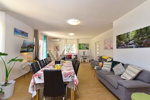 A spacious living area with a dining table, sofas, and a TV mounted on the wall. - Holiday home with swimming pool in a Mediterranean setting (Ližnjan)