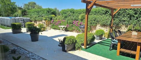 Un patio con un porche de madera, una parrilla y una piscina.