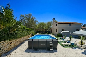 A swimming pool with a ladder, surrounded by a stone wall and greenery, with a house in the background. - Holiday home with swimming pool in a Mediterranean setting (Ližnjan)