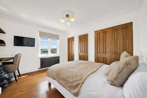 A bedroom with a bed, a desk, a chair, a radiator, a TV, and a window. - Berry Lodge I 5 Bed House Sleeps 10 -Hot Tub -Spa (Upminster)