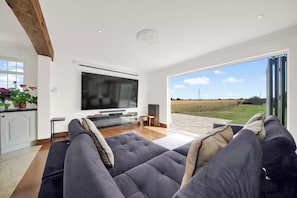 A modern living room with a large flat-screen TV, comfortable seating, and a view of the outdoors. - Berry Lodge I 5 Bed House Sleeps 10 -Hot Tub -Spa (Upminster)