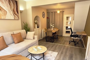 A living room with a sofa, coffee table, and a dining area with chairs and a table.