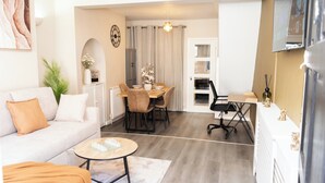 Un salon moderne comprenant un canapé, une table basse et un coin repas avec des chaises et une table.