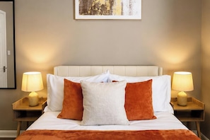 A hotel room with a bed, two bedside lamps, and a framed picture on the wall. - St Julian House- Town Centre- Castle Park- Hot Tub (Colchester)