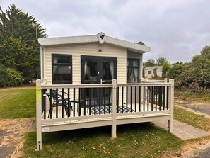 Casa móvel térrea com varanda, um pequeno deck e o número '57' visível na lateral.