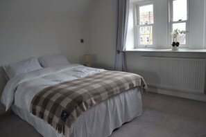 A bedroom with a bed, a window, a radiator, and a potted plant.