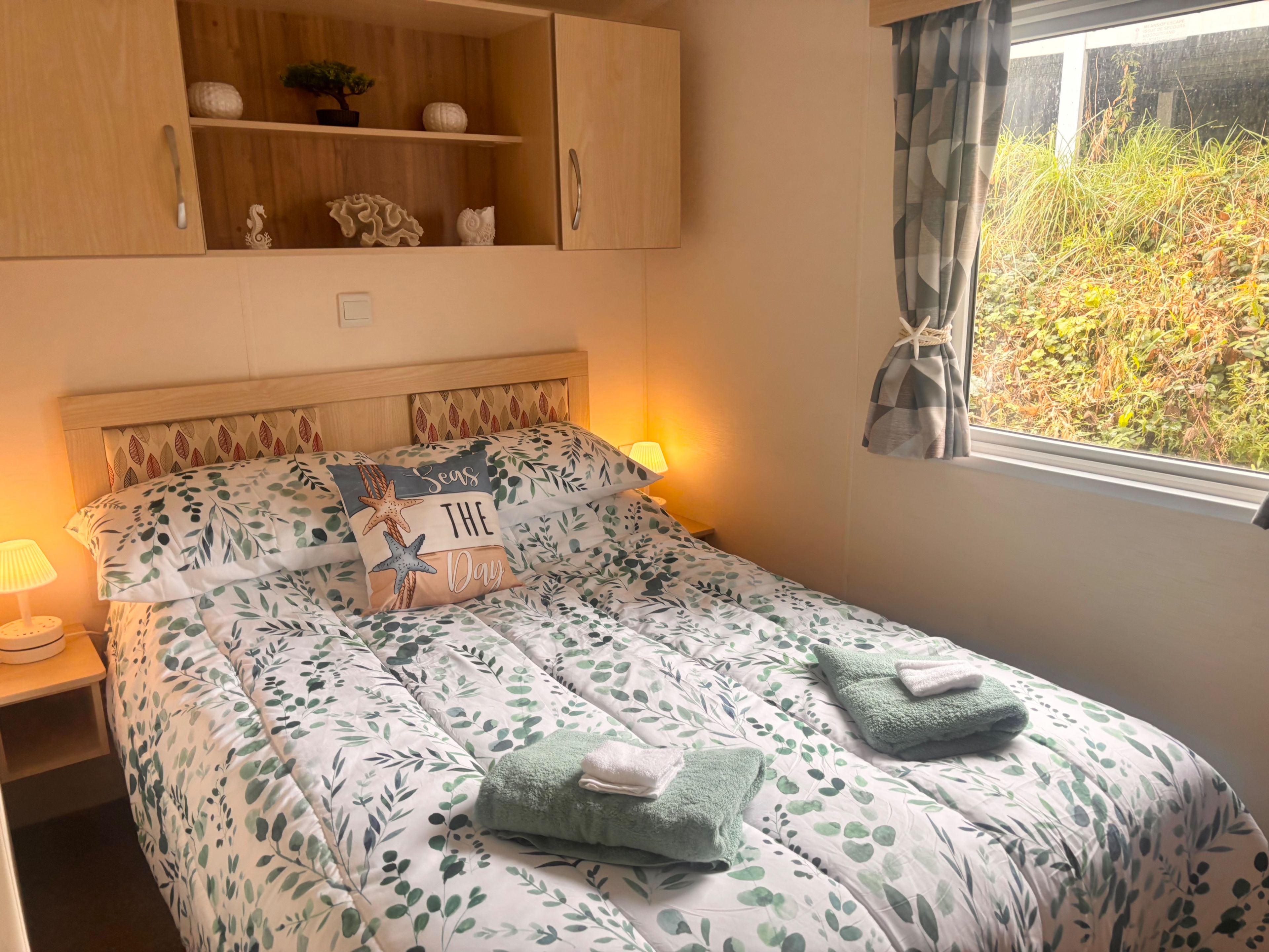 A bedroom with a bed, a nightstand, a wooden cabinet, and a window with curtains.