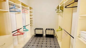 Un couloir étroit doté d’un sol à motifs, d’un ventilateur de plafond et d’étagères avec des porte-manteaux.