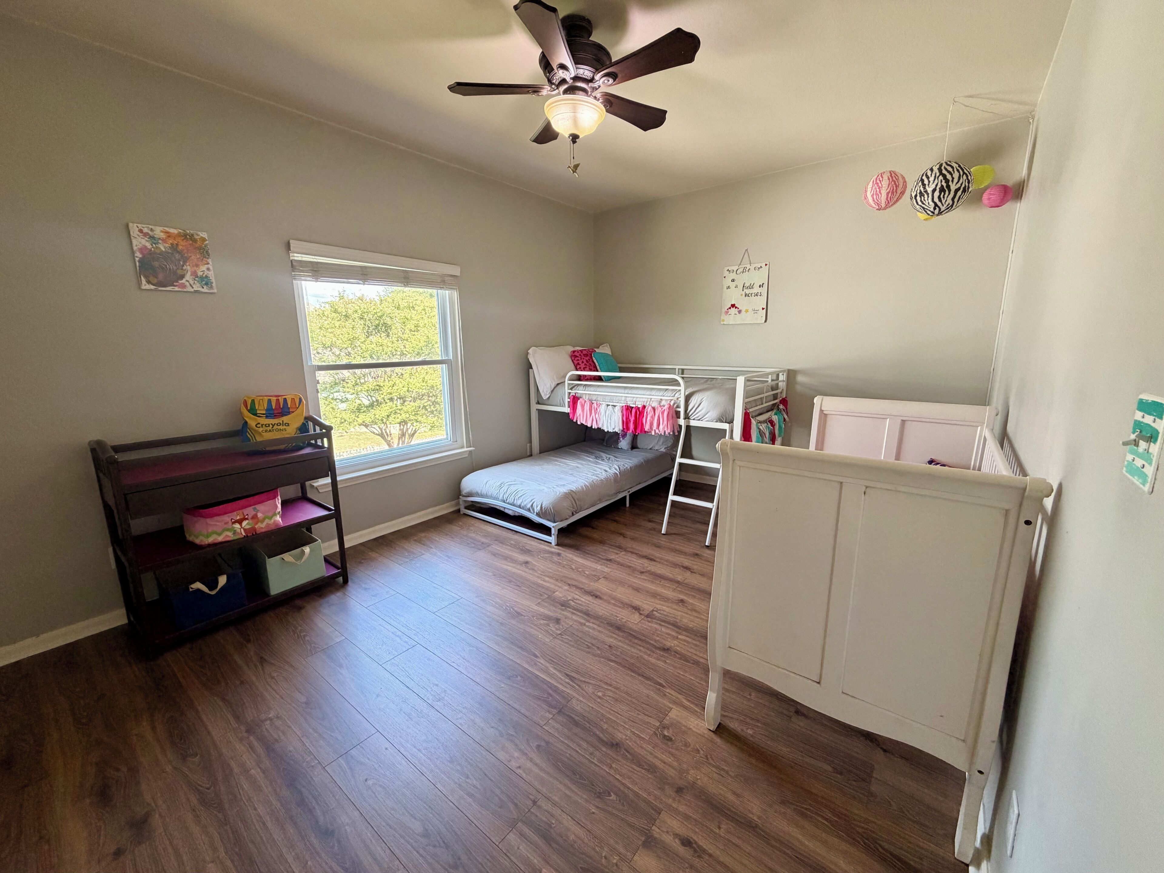 Une chambre d’enfant avec un lit superposé, un bureau, un ventilateur de plafond et une fenêtre.