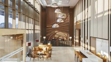 A modern hotel lobby with a reception desk, seating area, and large windows.