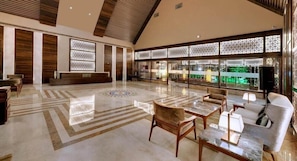 A spacious lobby with a reception desk, seating area, and large windows with decorative screens.