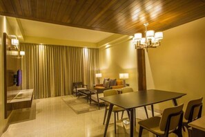 Habitación de hotel con comedor, sofá, araña y cortina.