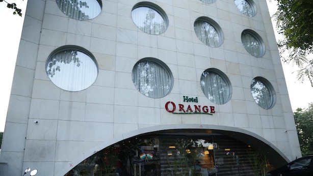 A hotel with a modern design, featuring a large arched entrance and multiple circular windows. - Hotel Orange (Agra)