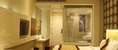 A modern hotel room with a bed, bedside table, and a shower area.