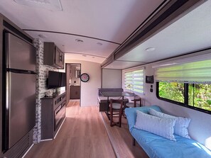 Un interior de caravana compacto con kitchenette, zona de comedor y espacio de estar.