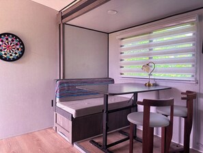A compact room with a small table, a bench, and a dartboard.