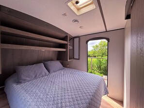 Une chambre à coucher avec un lit, des étagères intégrées, une fenêtre et un panneau indiquant la sortie.