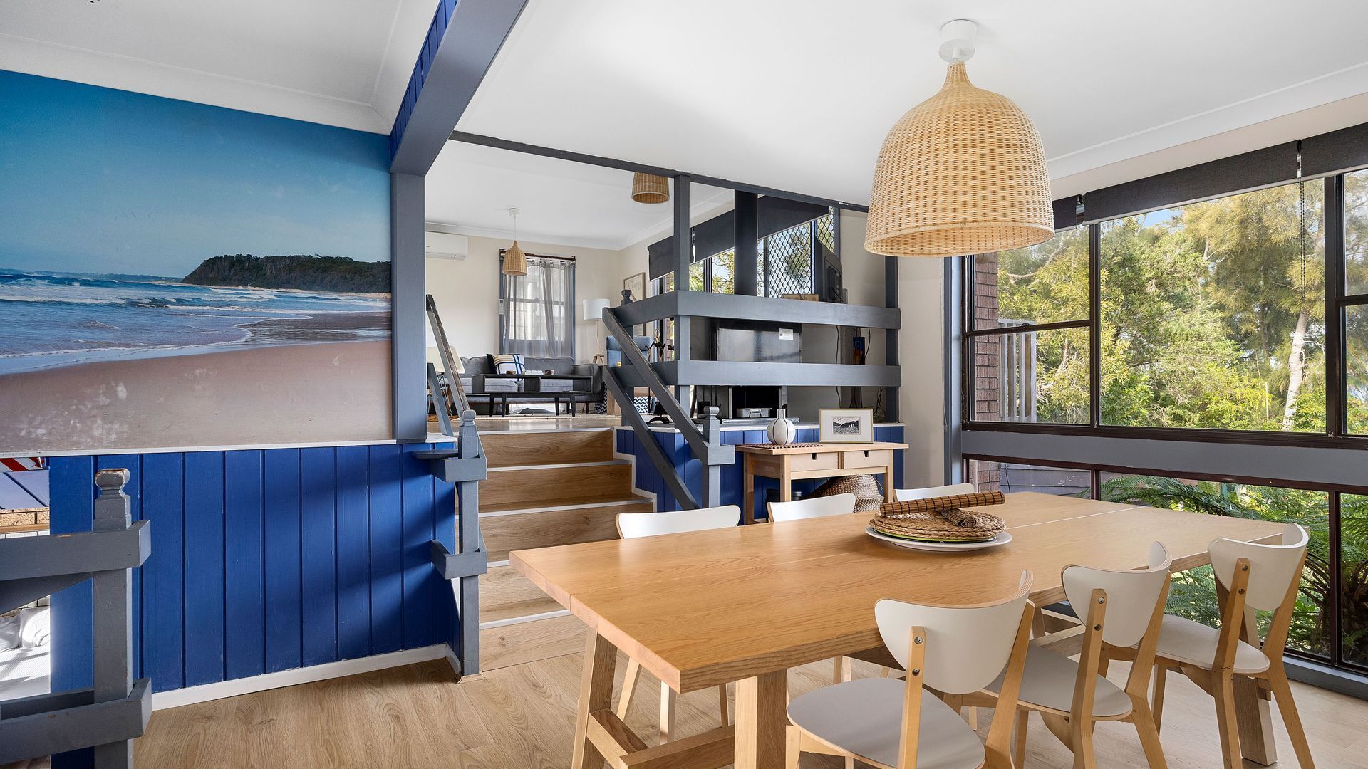 Une cuisine moderne dotée d’un grand îlot central, de planchers en bois et offrant une vue sur l’extérieur.