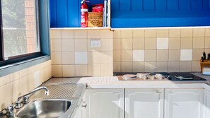A kitchen with a sink, stove, and blue cabinets. - Aqua, Pet Friendly Holiday Home Close to the Beach (Manyana)