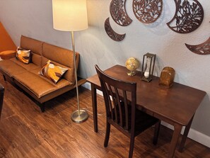 A room with a brown leather sofa, a wooden dining table, a globe, an hourglass, and decorative wall art.