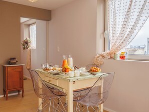 A dining area with a table set for breakfast, including fruits, bread, and beverages. - Lau'tentik by Interhome (Collombey-Muraz)