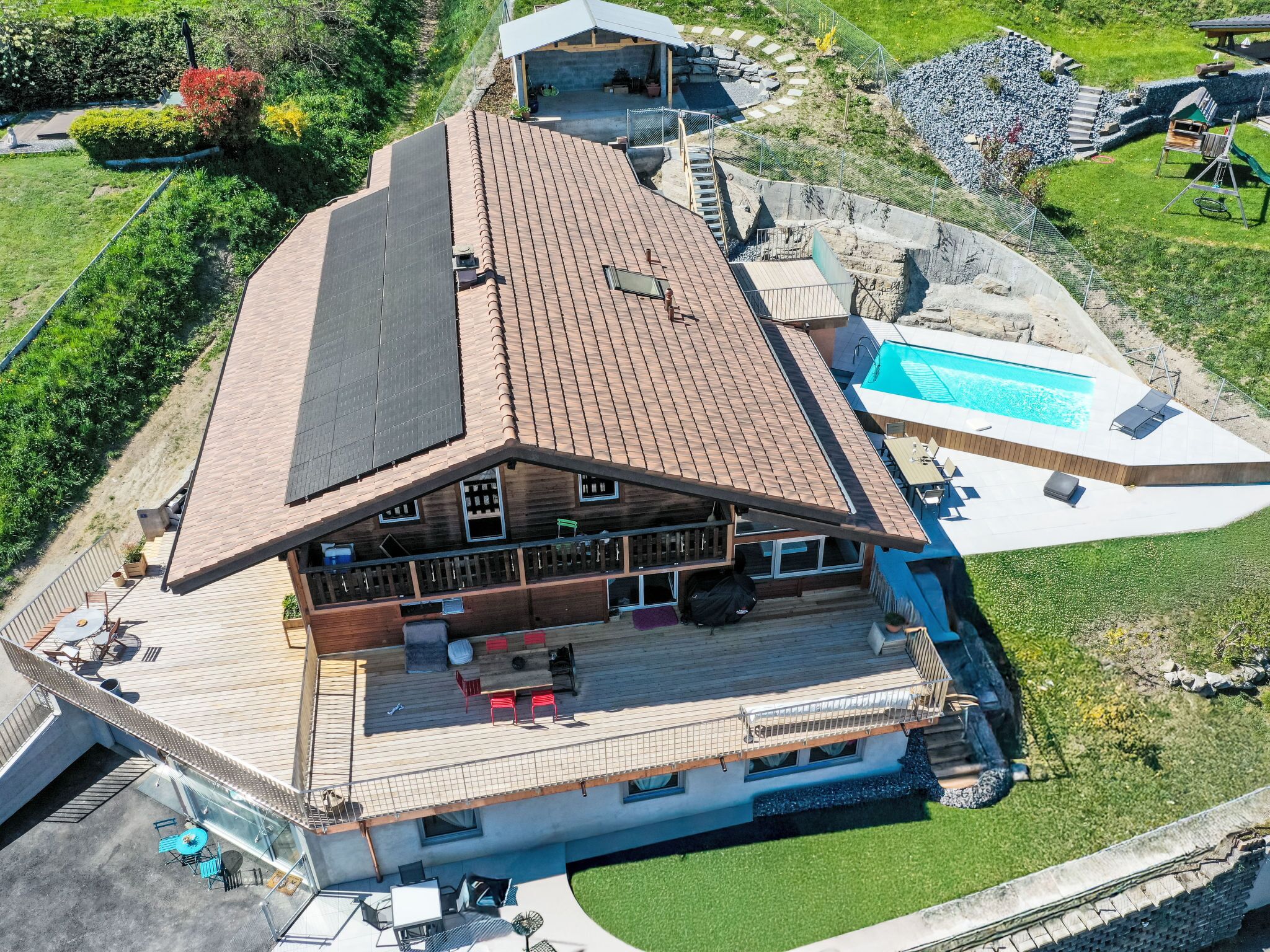 A large, modern building with a sloped roof, a swimming pool, and a deck area with outdoor seating.