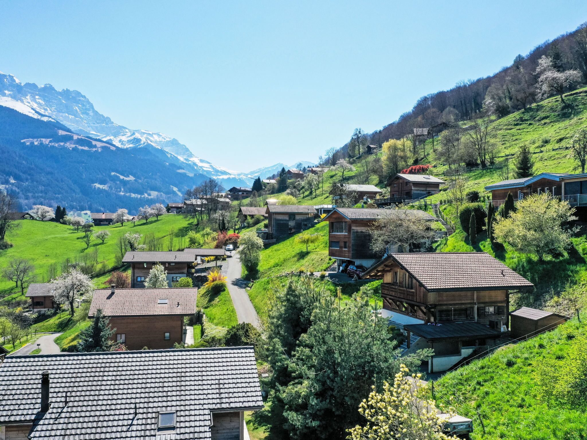 Un village perché sur une colline, avec ses maisons traditionnelles, une route sinueuse et une chaîne de montagnes en toile de fond.