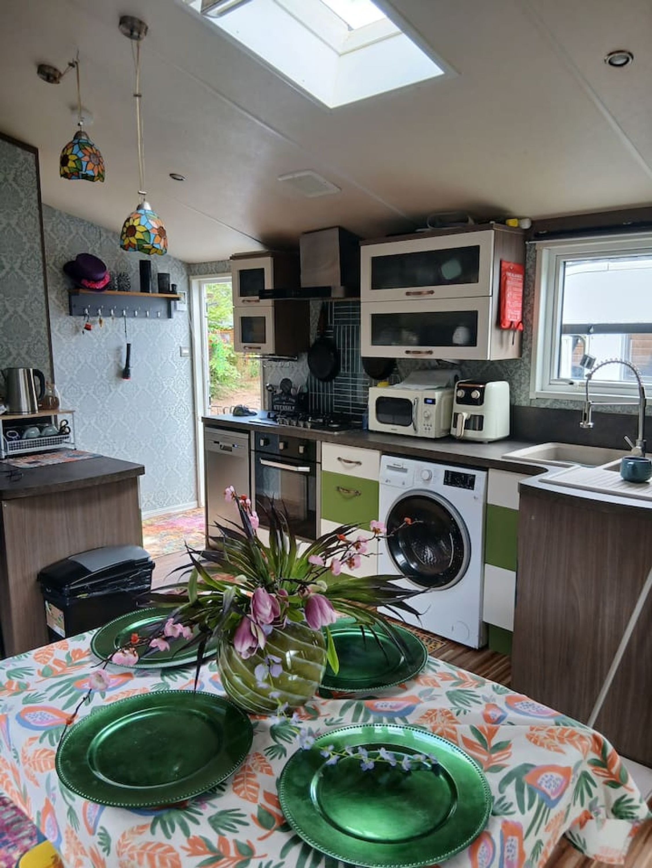 A compact kitchen with a washing machine, microwave, and a window above the sink.