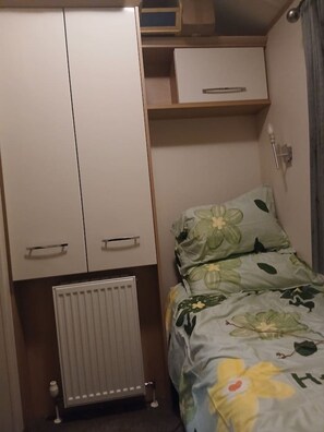 A bedroom with a bed, a wardrobe, a radiator, and a shelf. - Peacock Lodge Quirky Tranquil Home Away From Home (Auchterarder)